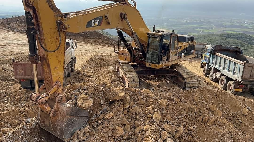 Excavadora trabajando sobre una ladera de roca