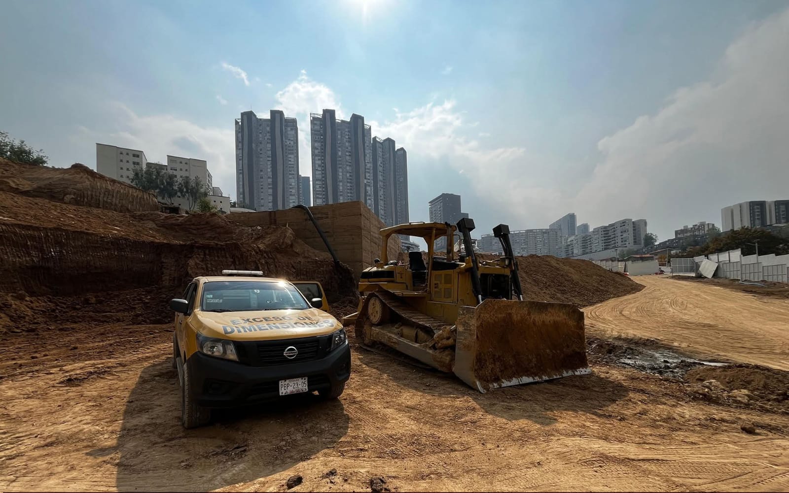 Excavación urbana con maquinaria de movimiento de tierras y edificios al fondo