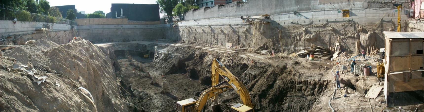 Vista panorámica de una excavación con maquinaria, taludes y elementos de contención